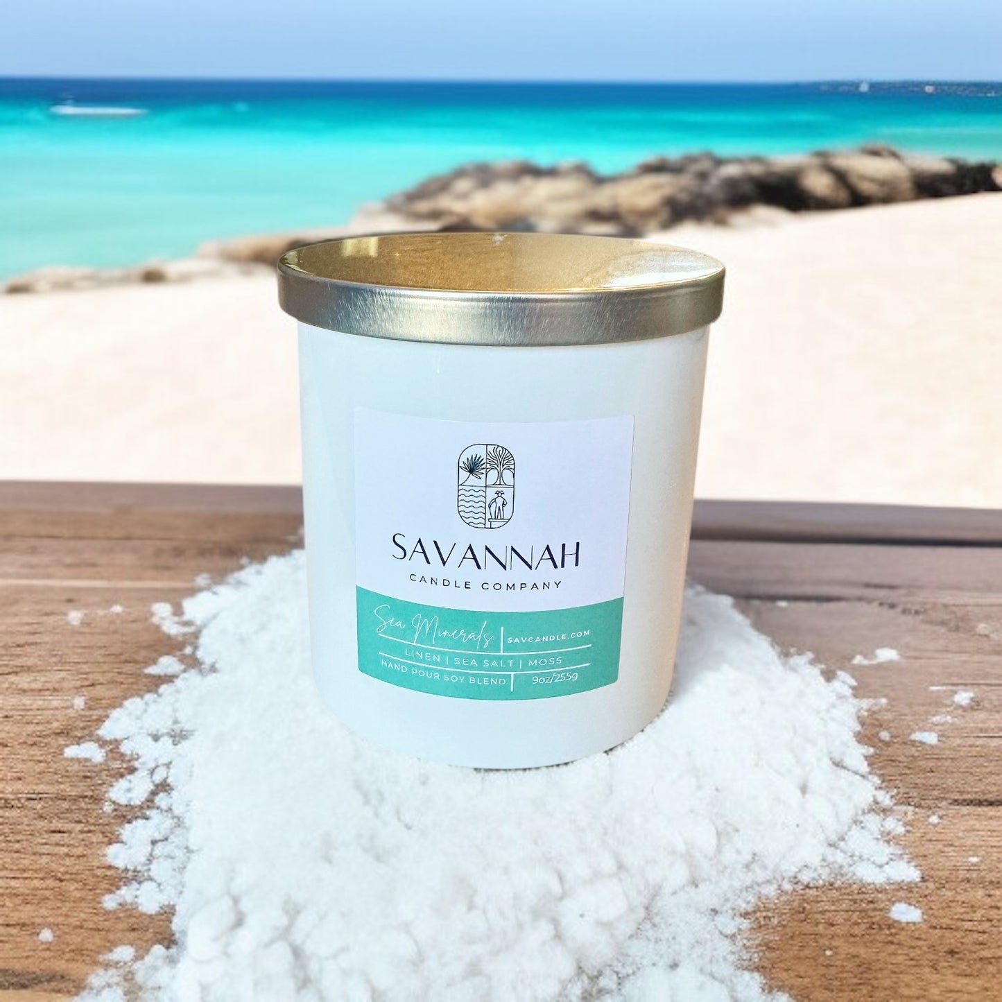 Candle from Savannah Candle Company on a sandy surface with a beach background. The fragrance of this scandal is sea minerals. It smells like sea salt, ocean, air, and water.