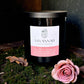 Savannah Candle Company candle with a pink rose on a dark background.   Rose and moss fragrance. 