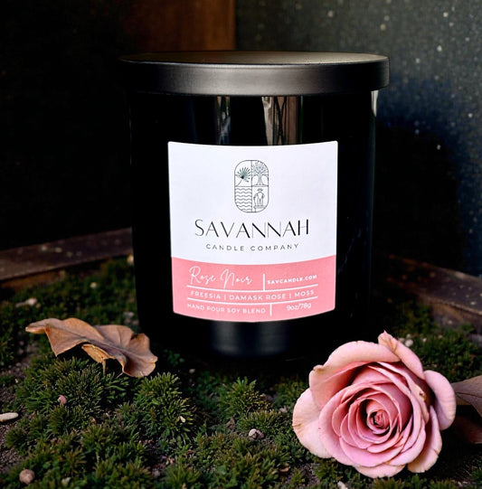 Savannah Candle Company candle with a pink rose on a dark background.   Rose and moss fragrance. 